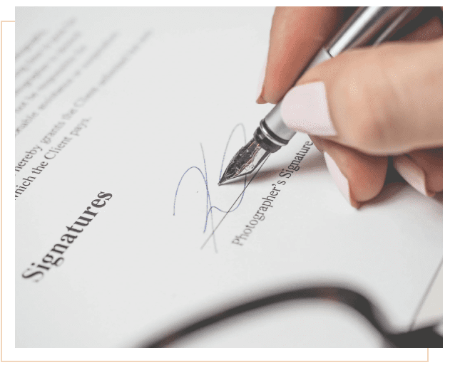 A person signing a document with a pen.